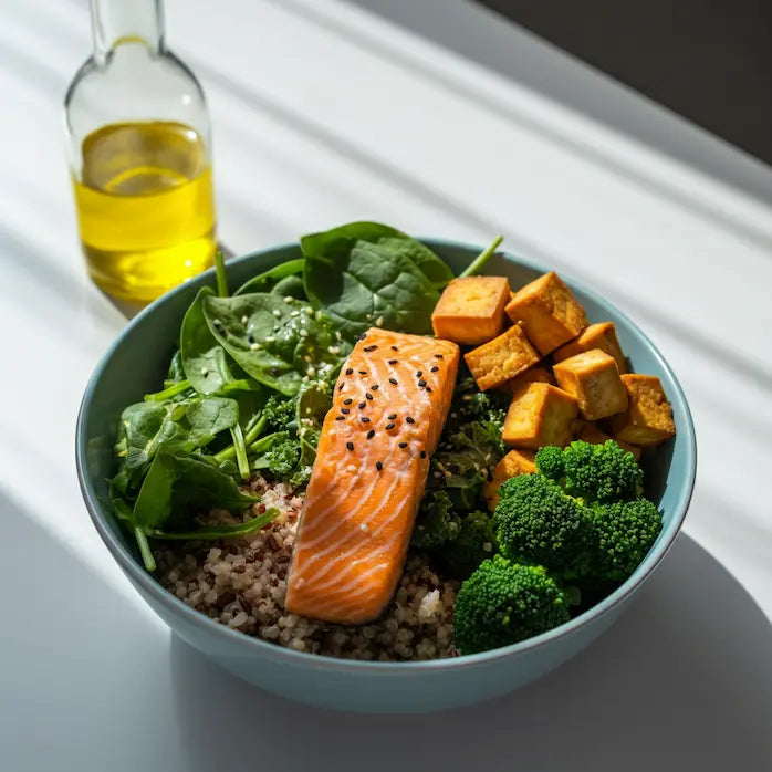 Bowl with salmon, vegetables, and a bottle of oil on a white surface